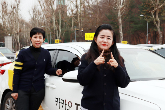 파트너스 산하 운수사에서 카카오T 블루 크루로 근무중인 기사(오른쪽)가 "만나서 반갑습니다"라는 의미의 수어를 하고 있다. <카카오모빌리티 제공>